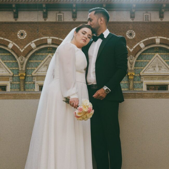 Heiraten in Dänemark: Ein Brautpaar in eleganter Kleidung steht liebevoll zusammen in einem historischen Gebäude nach der Trauung.