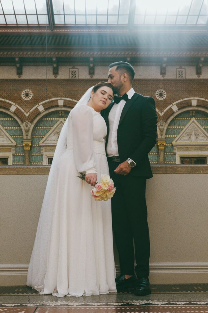 Heiraten in Dänemark: Ein Brautpaar in eleganter Kleidung steht liebevoll zusammen in einem historischen Gebäude nach der Trauung.