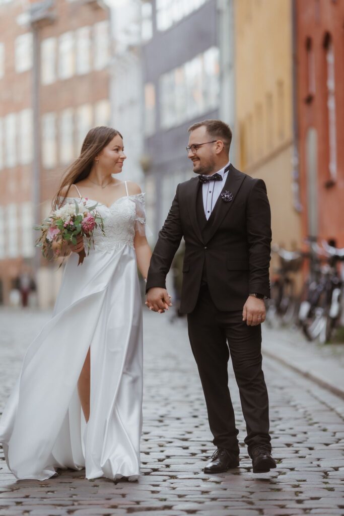 Heiraten in Dänemark: Ein Brautpaar spaziert Hand in Hand durch die gepflasterten Straßen von Kopenhagen nach der Hochzeit.